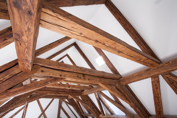 Die Knoten des alten Dachstuhls von unten, Sparren und Streben vor den weißen Flächen des Ausbaus