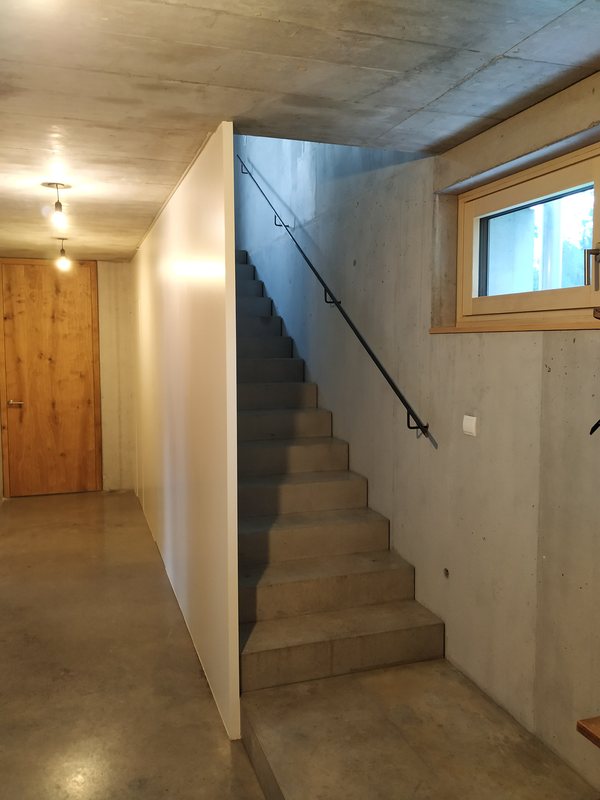Die Treppe zwischen Sichtbetonwand und weißer Wand, seitlich ein Oberlicht