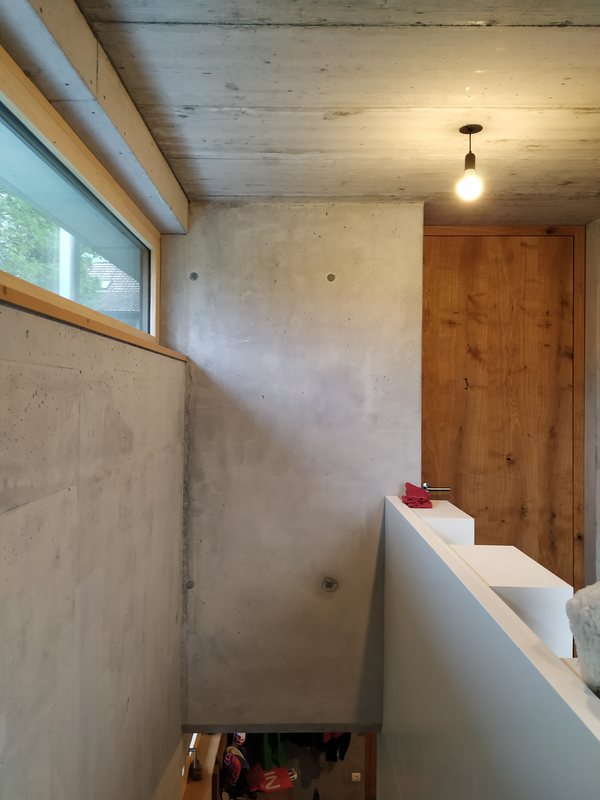 Blick von der Treppe ins Obergeschoß, Sichtbeton und Holztür