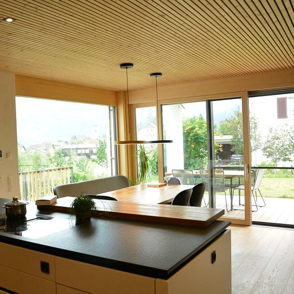 Essküche unter der Holzlattendecke, raumhohe Fenster zur überdachten Terrasse und zum Garten