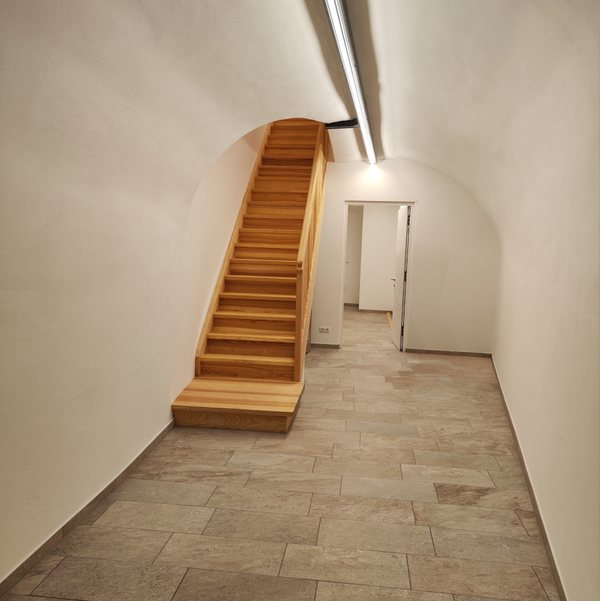 Der gewölbte Eingang mit erneuertem Steinboden, dahinter die neue Treppe aus Eschenholz