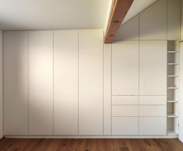 Einbauschrank über die ganze Wand des Elternzimmers, darüber ein sichtbarer Sparren unter der Dachschräge