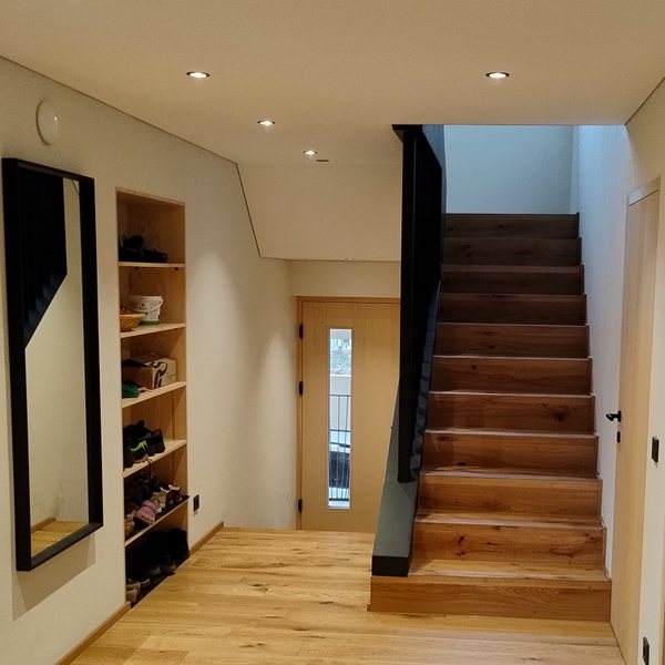 Die neue Treppe aus Holz an derselben Stelle, links ein eingebautes Regal, darüber die glatte Decke