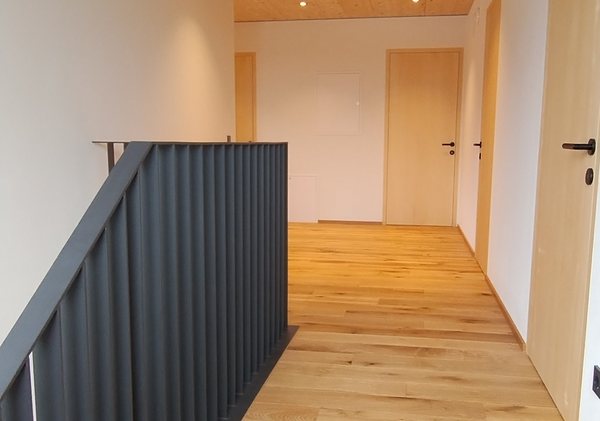Der Gang im aufgestockten Obergeschoß, Lamellengeländer am Treppenauge, darüber die sichtbare Holzdecke