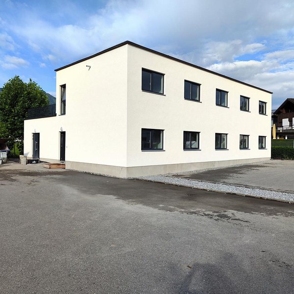 Die Wohnanlage von der Zufahrt, zwei Geschoße, weiß verputzt, Flachdach