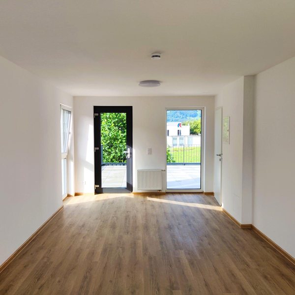 Eine der Wohnungen vor dem Einzug, Wohnraum mit Fenster und Tür ins Freie